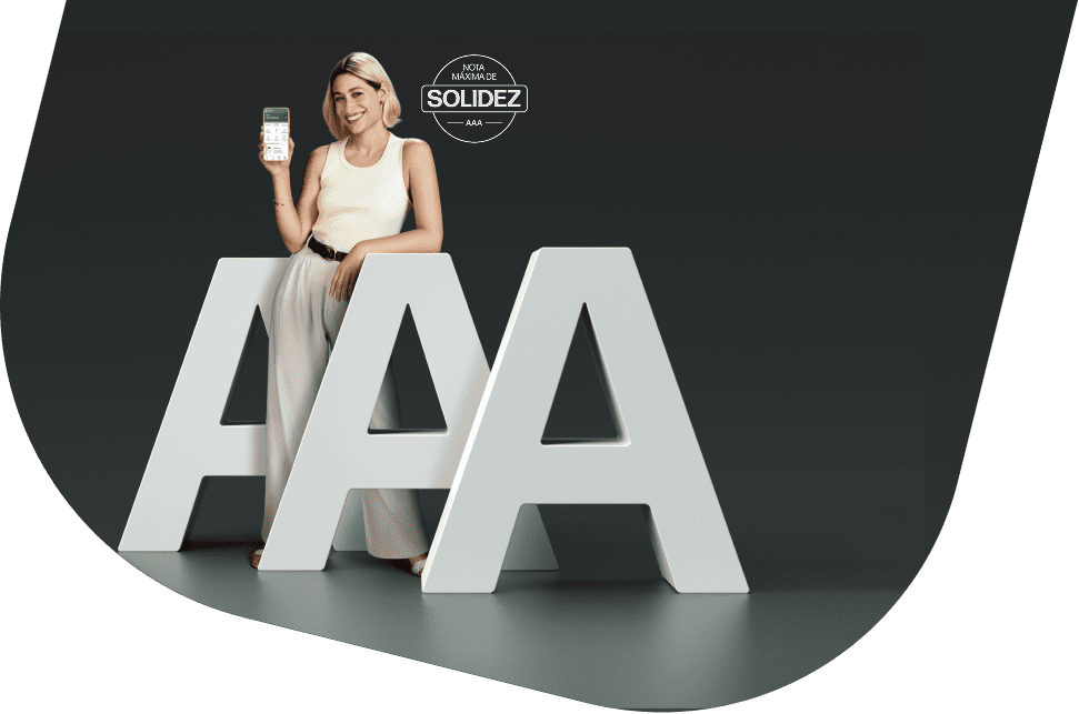 Atriz Luisa Arraes, branca, de cabelo loiro e expressão sorridente, segurando um celular com o aplicativo do PagBank aberto. Ela está vestindo uma regata branca e uma calça bege. Sobre a imagem há um selo: "nota máxima de solidez AAA".