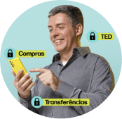 Homem branco sorridente segura um celular amarelo, simbolizando segurança e proteção da conta PagBank.