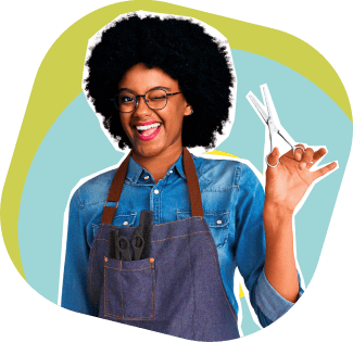 Mulher negra de cabelo cacheado, sorridente e piscando um olho, vestindo avental jeans com tesouras no bolso. Ela segura uma tesoura de cabeleireiro na mão direita, transmitindo confiança e entusiasmo. O fundo possui formas geométricas em tons de azul e verde. A imagem representa pequenos empresários e empreendedores, reforçando a comunicação do Seguro Empresarial do PagBank.