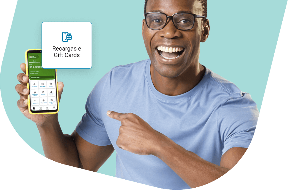 Homem preto segura um celular com o aplicativo PagBank aberto, mostrando a área de recargas para celular e serviços como Spotify, Uber, Google Play, Steam, Xbox, Minecraft e PlayStation.