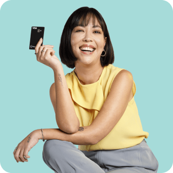 Mulher asiática sorridente segura um cartão PagBank, representando proteção e segurança do Seguro Cartão Protegido.