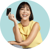 Mulher asiática sorridente segura um cartão PagBank, representando proteção e segurança do Seguro Cartão Protegido.