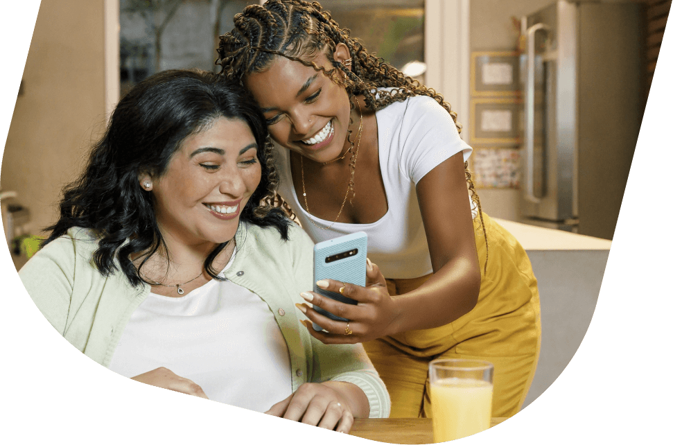 Duas mulheres observam o app PagBank no celular, representando praticidade na pré-autorização de pagamentos.